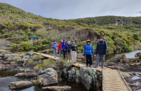 Hikers cross a wooden boardwalk