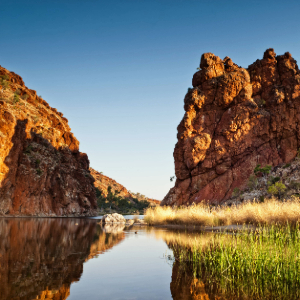 Calm river between towering red rock formations.