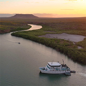 Boat cruising down a winding river at sunset.