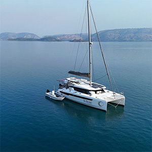 Catamaran anchored in calm water surrounded by hills.