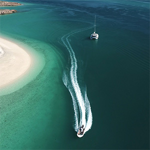 Two boats moving in a turquoise bay.