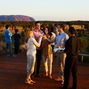 Guests toast while enjoying drinks and a stunning view of Uluru at sunset.