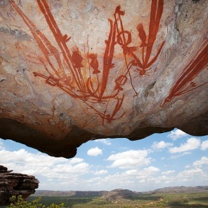 Ancient indigenous rock art is painted on a rock overhang.