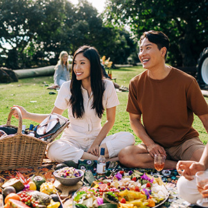 Two people enjoying a picnic of fresh fruit on the lawn.