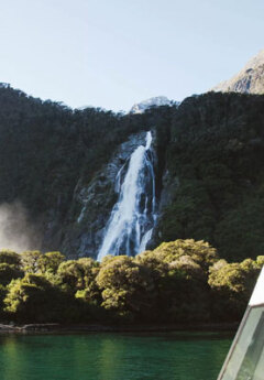 A waterfall pours out of the side of a rocky mountain in Milford Sound