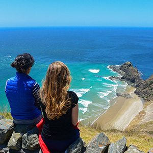 Couple enjoying ocean views near Cape Reinga, North Island