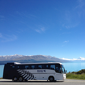Image of a coach with snowcapped mountains at the background on a sunny day