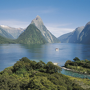 A boat cruises past Miter Peak in Fiordland on a sunny day