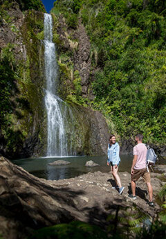 A couple walking towards Karekare Falls