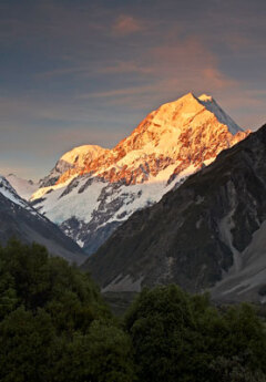 The tip of Mount Cook is bathed in an orange light