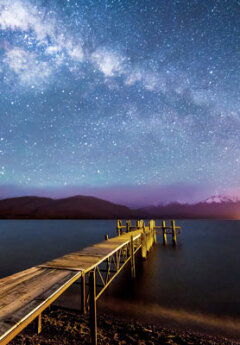 A wooden wharf is pictured under a starry night sky