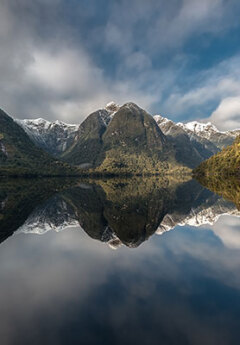 Mountains reflect off the still water in Doubtful Sound