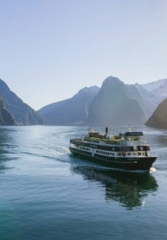 Scenic boat cruising through the dramatic cliffs and calm waters of Milford Sound, Fiordland, New Zealand