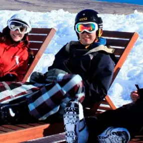 4 skiers relaxing on loungers in the sunshine