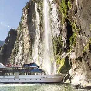 Boat getting close to a waterfall in Fiordland National Park.