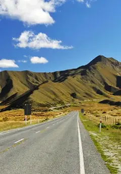 A road twists and disappears into a mountain called the Lindis Pass