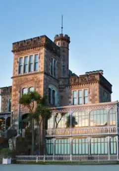 The sun sets onto Larnach Castle, making the windows glow and the building appear orange