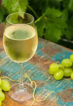 Image of a glass of white wine and green grapes