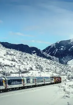 Tranzalpine train heading towards mountains in the winter