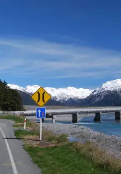 Bridge over a clear blue river, and Arthur's Pass in the background