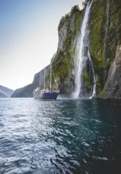 The Milford Mariner cruises alongside a cascading waterfall in Milford Sound.