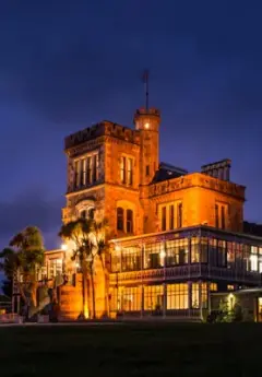 Larnach Castle illuminated in orange lights at nighttime