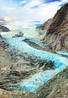 A blue icy glacier curves downward in between mountains