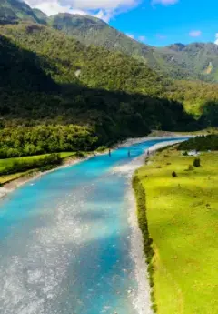 Turquoise river winding through lush valley and mountains.