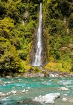 Waterfall into blue waters in green lush forest