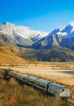 The TranzAlpine train glides through the valley floor