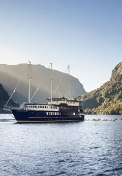 A boat cruising Milford Sound on a bluebird day