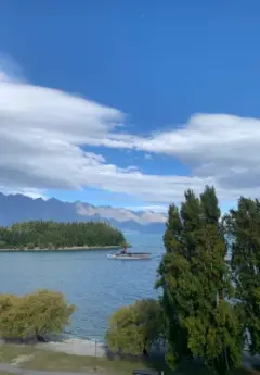 Boat on lake with trees and mountain backdrop.